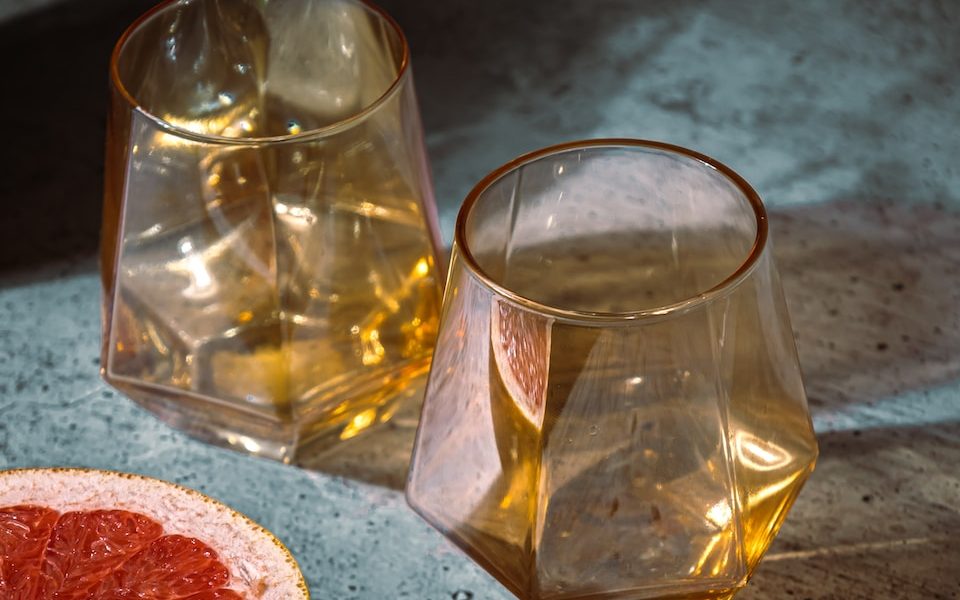 a glass and a fruit on a table Sweet Wines From Around the World